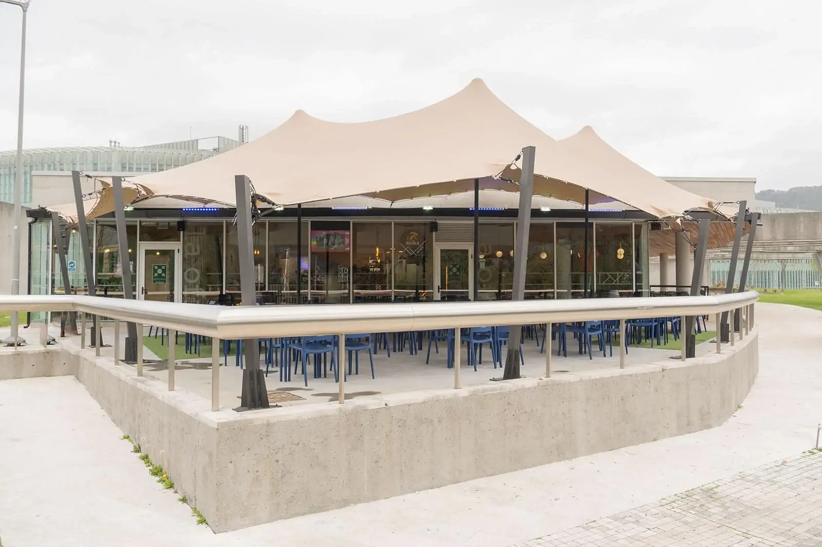 Fachada de La Ofi con la terraza cubierta por la carpa tensada y la barandilla de acero